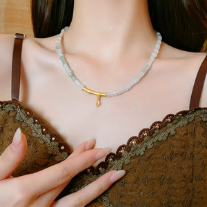 Detail of bamboo-style necklace with light green jade beads and gold leaf pendant