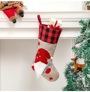 Detail of a Christmas stocking with a gnome figure on a red and black plaid cuff