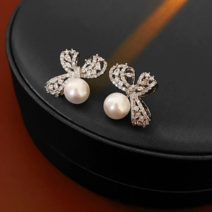 Gros plan de boucles d'oreilles nœud en argent avec zircons et perles blanches chic