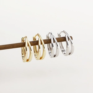 U-shaped sterling silver hoop earrings in gold and silver finishes on a wooden display