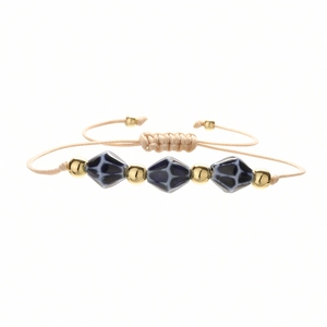 Detail of hand-woven bracelet with deep blue geometric ceramic beads and gold accents