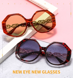 Detail view of Greek fret metal hardware and logo engraving on tortoise sunglasses