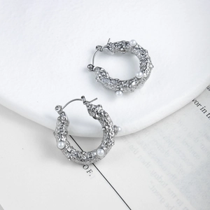 Boucles d'oreilles argentées texture lave avec perles et strass sur socle blanc