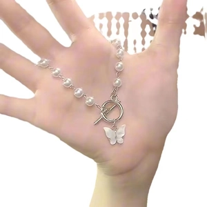 Detail of elegant butterfly pendant with shell texture on white pearl bracelet
