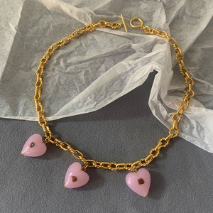 Detail of gold chain necklace with pink Murano glass heart charms and toggle clasp