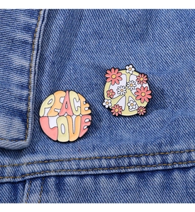 Detail of Peace Love and floral peace sign enamel brooches on a blue denim jacket