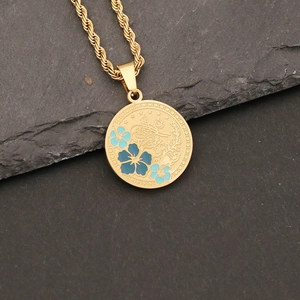 Detailed macro view of gold eye pendant necklace with blue enamel and twist chain on slate