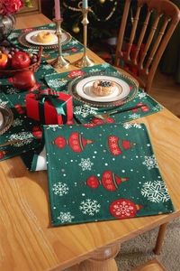 Green Christmas table runner set with red ornaments and snowflakes on a wooden table