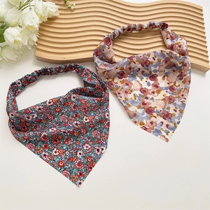 Close-up of floral satin headscarf with elastic band on a wooden tray with flowers