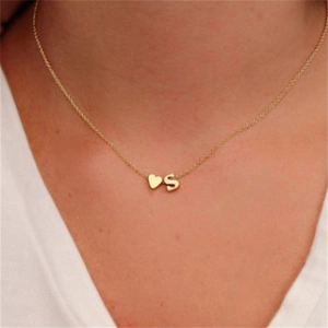 Primo piano di una collana con ciondolo a cuore e lettera S dorata su una donna