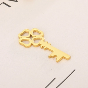 Macro detail of golden stainless steel four-leaf clover key pendant with polished finish