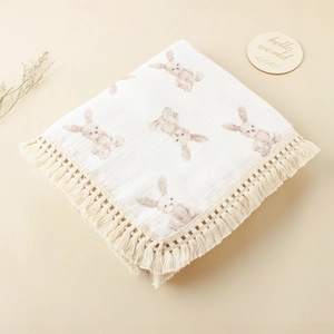 Detail of soft cotton baby blanket with bunny print and delicate tassel fringes