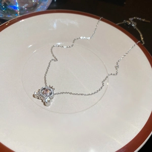 Detailed close-up of a silver carriage pendant with a pink heart crystal on a tray