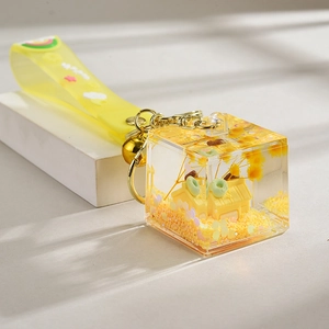Detail of creative house keychain with a yellow silicone strap and gold glitter accents