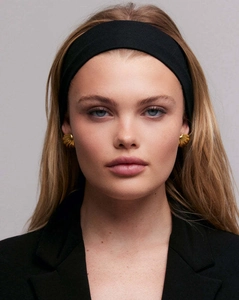 Detail of 18K gold shell earrings and a black minimalist headband on a model