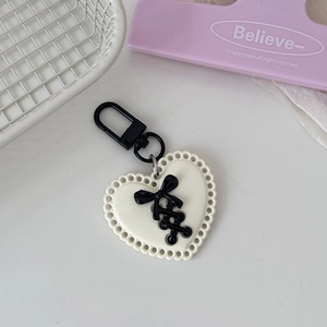 Detail of cream white heart keychain with black ribbon bow and metal clasp