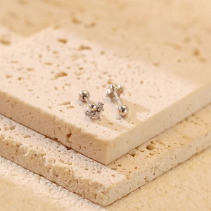 Macro shot of silver star stud earrings with zirconia stones on natural stone texture