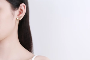 Detail view of 18K gold earrings featuring a creative liquid metal lava drop design on model