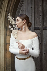 Detail of elegant gold metal mirror belt on white off-shoulder dress with stone background
