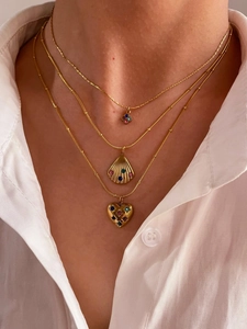 Detail of layered gold necklaces with shell and heart colorful gemstone pendants