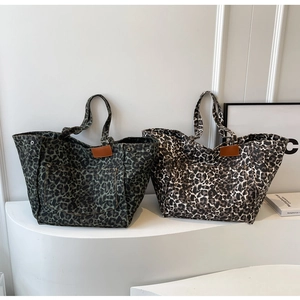 Close-up of leopard print canvas tote bags with leather patches and metallic rivets