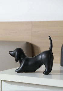 Detailed view of a matte black ceramic dachshund dog sculpture in a playful pose