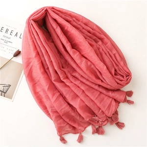 Detail of coral pink cotton linen scarf featuring shimmering threads and tassel edges