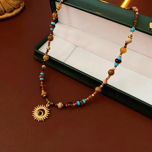 Vintage sun pendant necklace with natural stone beads on a textured surface