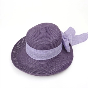 Detail of purple straw hat featuring intricate woven texture and decorative bow accent
