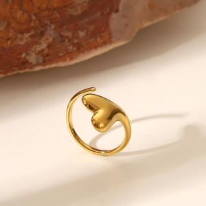Primo piano dettagliato di un anello dorato a forma di cuore su una base di pietra naturale