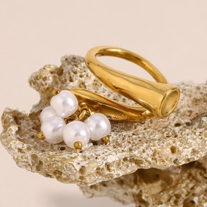 Macro detail of 18K gold irregular ring with dangling white pearl tassels on coral stone