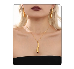 Close-up of golden teardrop pendant necklace and streamline earrings on a model