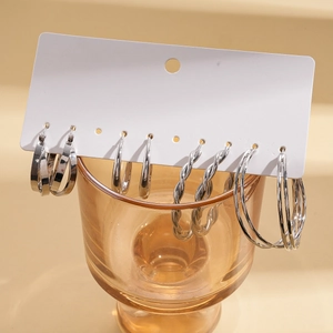 Detail of silver geometric hoop earrings set with smooth and twisted textures on card