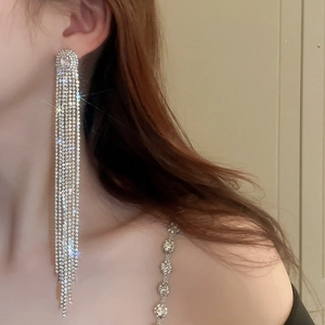 Close-up of sparkling rhinestone tassel earrings worn by a model in a luxury setting