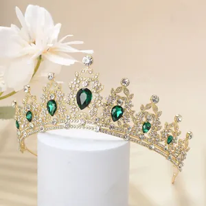 Detail of luxury gold crown with emerald green waterdrop gems and white rhinestones