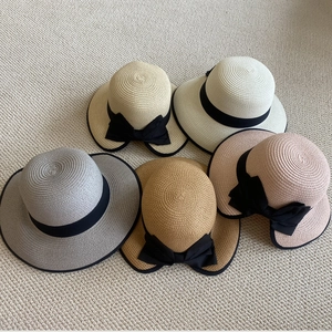 Detalle de sombreros de paja de ala ancha con cintas negras en colores neutros
