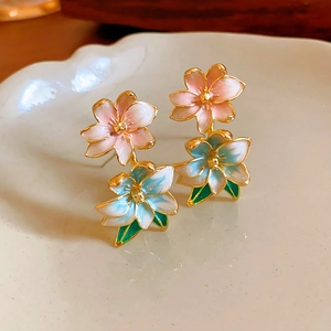 Detail of pink and blue enamel flower earrings with green leaf and gold finish