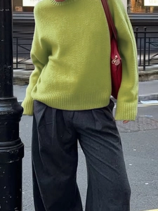 Street style view of a light green knit crewneck sweater with dark grey wide-leg trousers