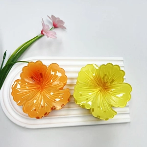 Dettaglio macro di fermagli per capelli a forma di fiore in resina arancione e giallo vivace
