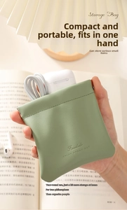 Detail of sage green PU leather pouch holding white earphones and a charging cable