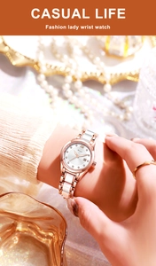 Détail de montre quartz or rose avec index en strass et dateur au poignet d'une femme
