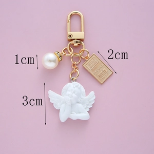 Close-up of vintage baroque key ring with Cupid angel, white pearl and gold bar pendant