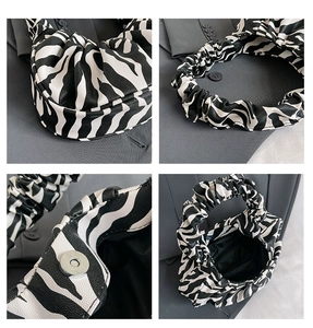 Detail view of zebra print cloud bag featuring pleats and a magnetic metal buckle