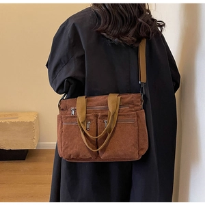Brown corduroy shoulder bag with multiple zippered pockets shown on model in casual style
