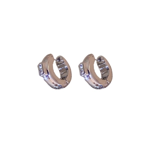 Minimalist silver metal hoop earrings with sparkling small inset diamonds on white background