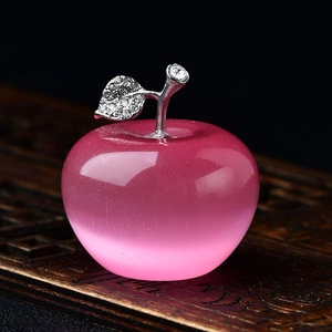 Detailed view of pink crystal apple decor with silver leaves on carved wooden base
