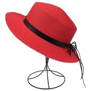 Detailed texture of red straw sun hat with black leather band and bow on display