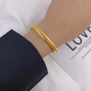 Detail of gold wheat ear weave bracelet worn with a black suit for a chic style