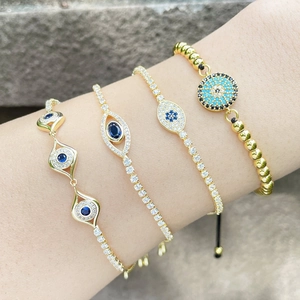 Gold evil eye charm bracelets set with blue and clear rhinestones on model's wrist