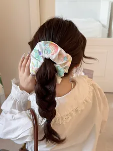 Detail of white satin scrunchie with floral embroidery worn on a braided hairstyle
